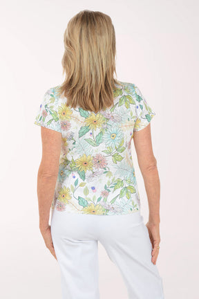 Woman wearing a floral print top and white pants on a white background