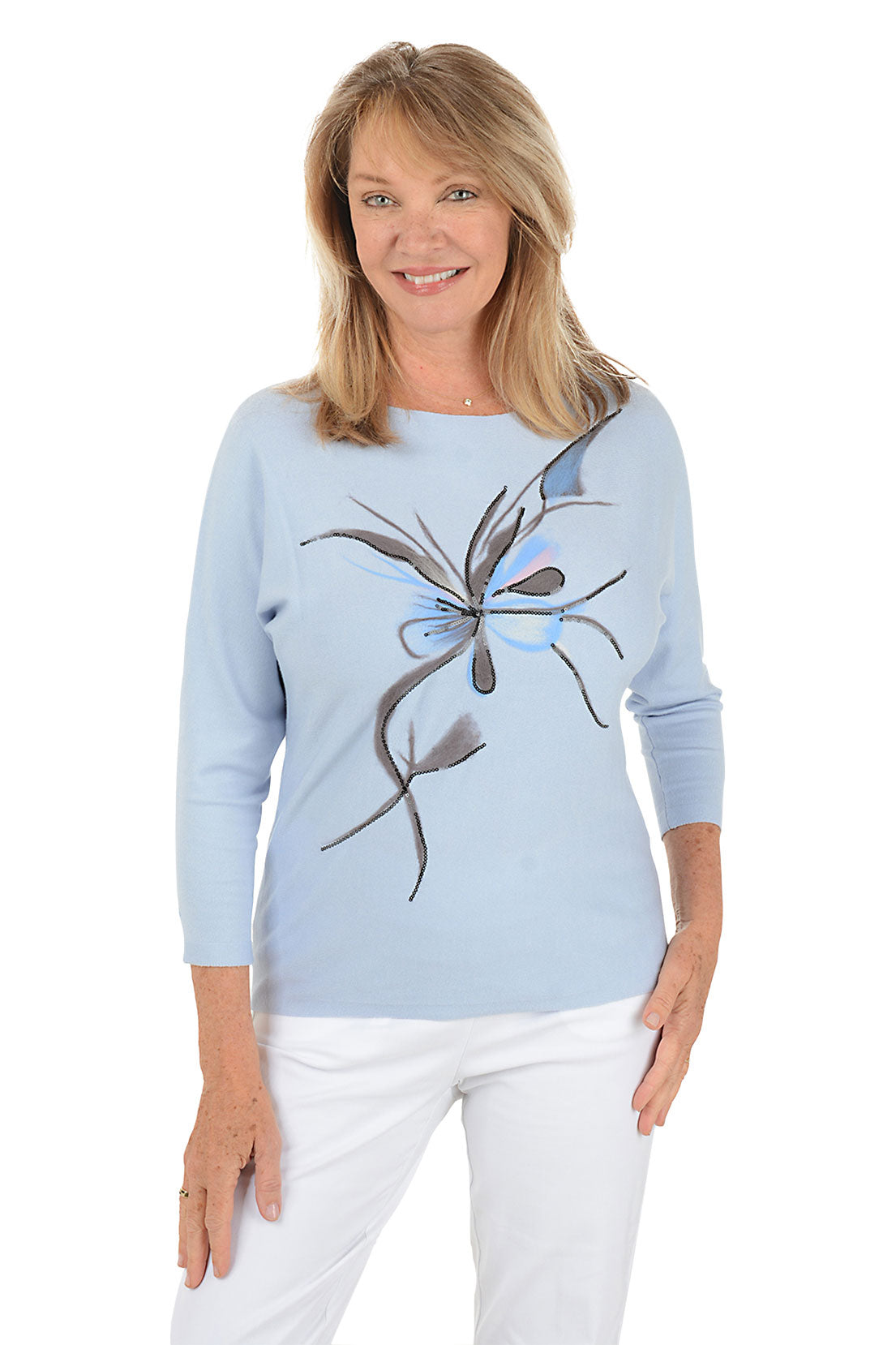 Woman wearing a light blue sweater with a flower design on a white background.