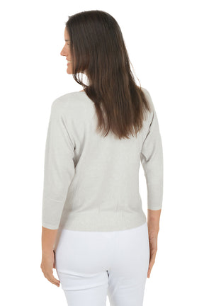 Woman wearing a light gray sweater with floral designs on a white background. Back shot.