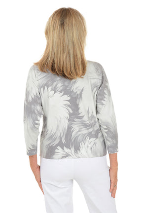 Woman wearing a 3/4 sleeve gray dandelion floral sweater with white pants on a white background. Back shot.