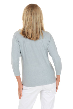 Woman wearing a light blue sweater with silver floral embroidery on a white background. Back shot.