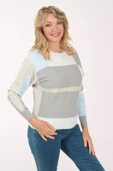 Woman wearing a colorful sweater and blue jeans on a white background