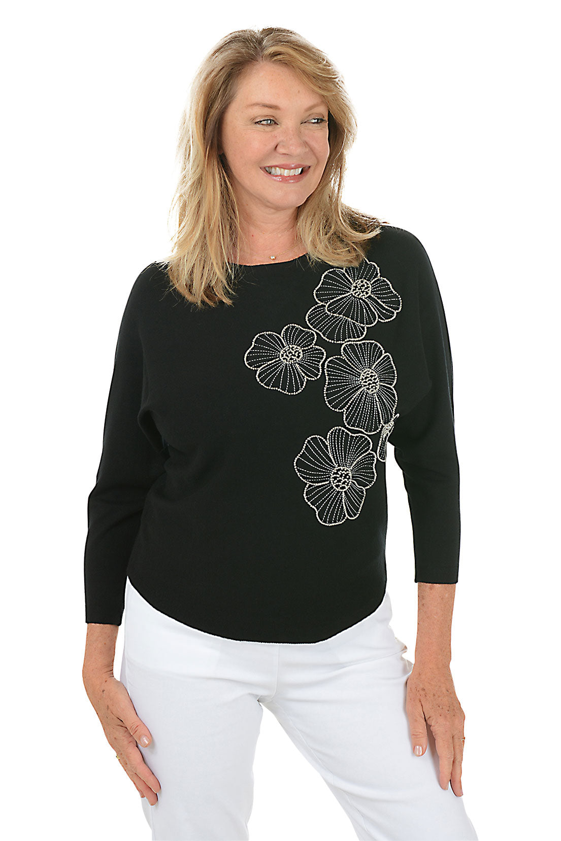 Woman wearing a black sweater with floral designs on a white background.