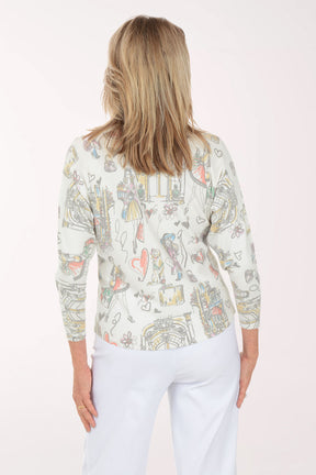 Woman wearing a long-sleeve top with colorful graphic design on a white background