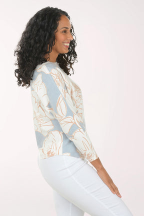 Woman wearing a light blue floral-patterned sweater against a white background