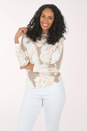 Woman wearing a floral blouse and light blue pants on a white background