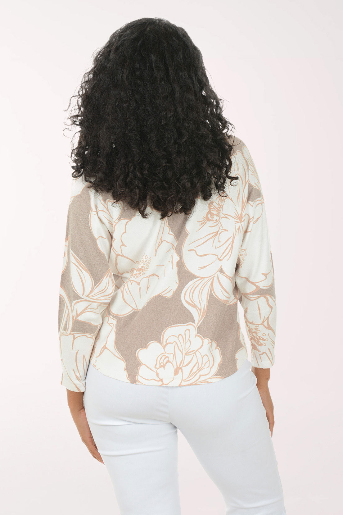 Woman wearing a floral blouse and light blue pants on a white background
