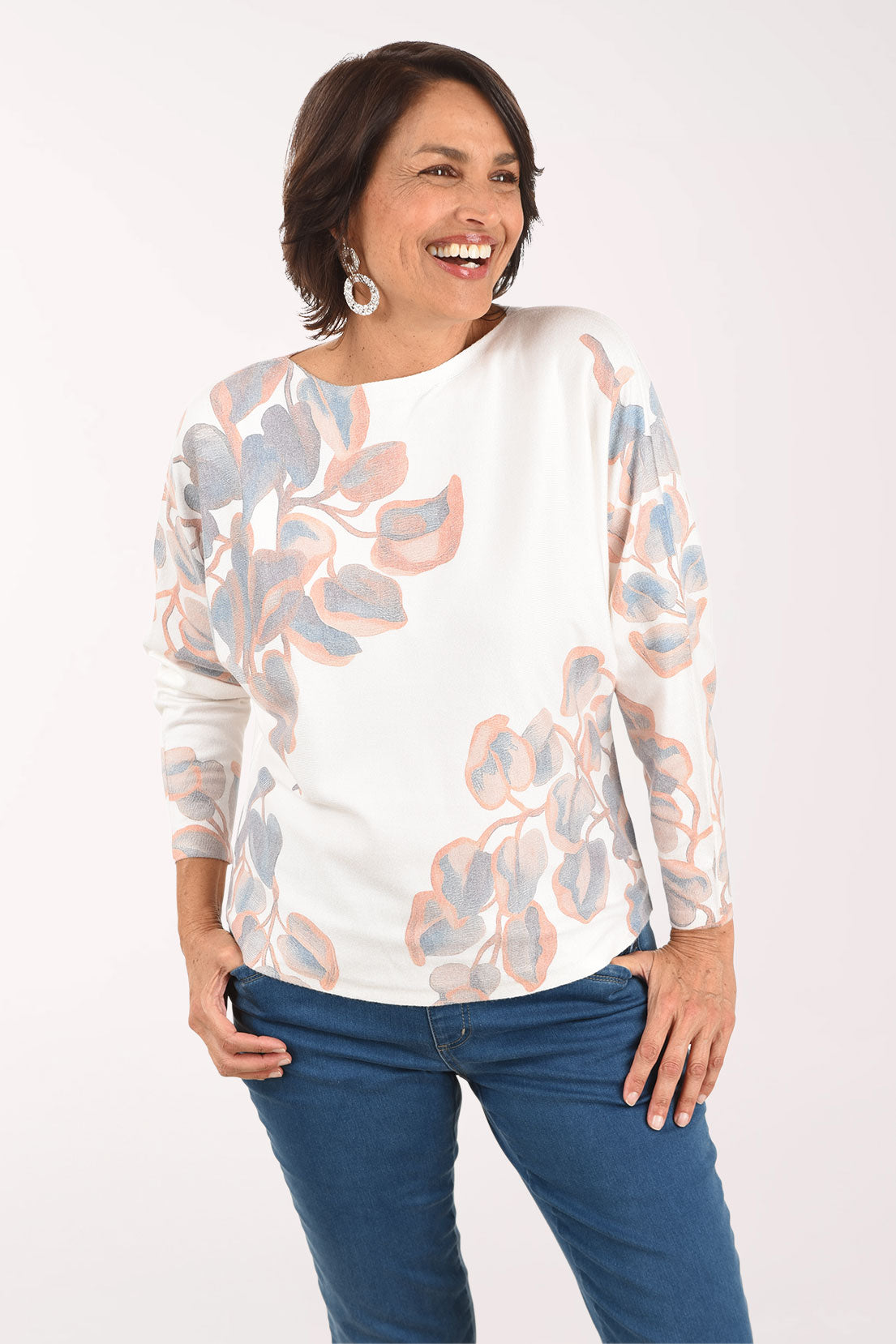 Woman wearing a floral blouse and blue jeans on a white background
