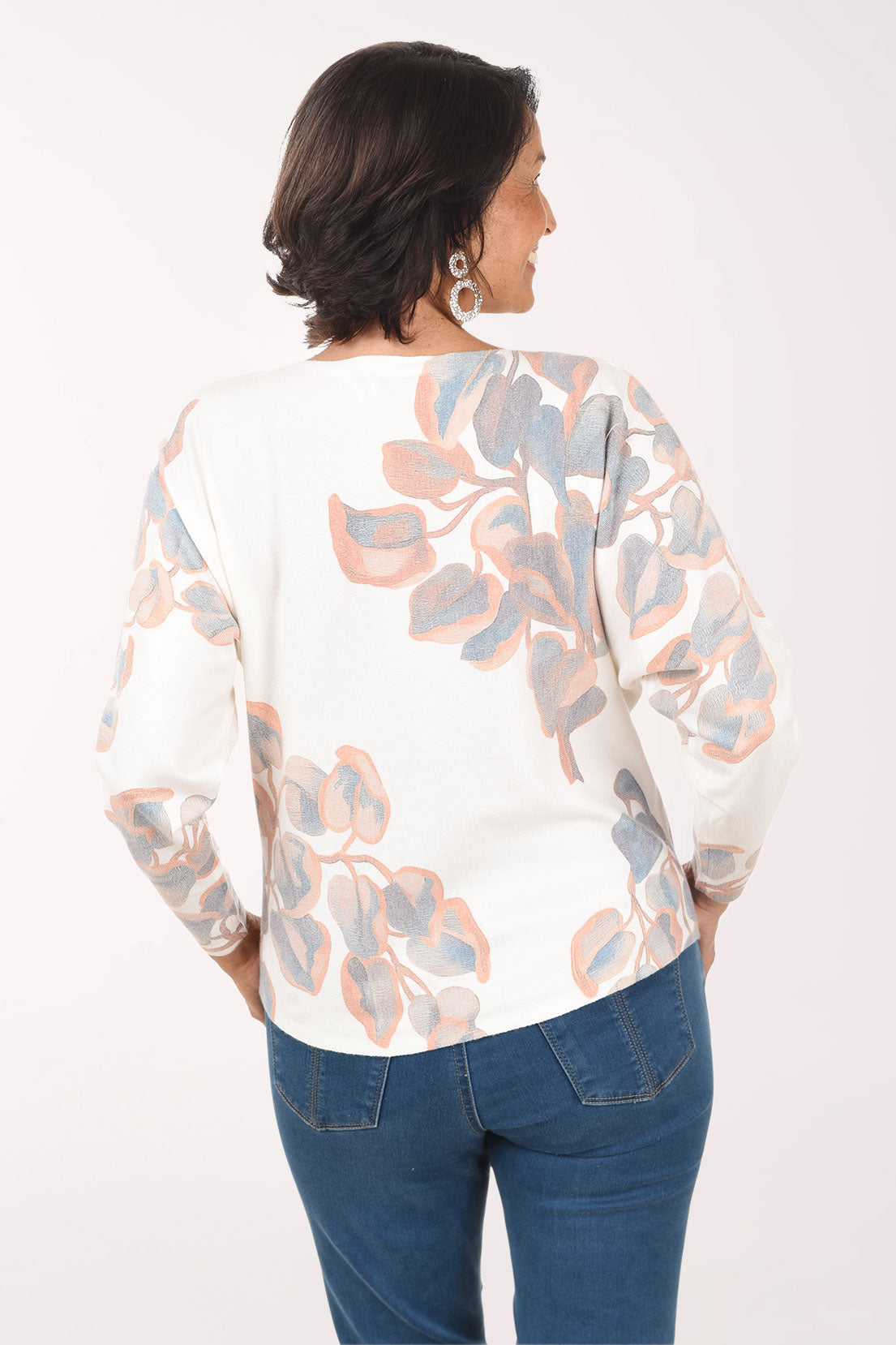 Woman wearing a floral blouse and blue jeans on a white background