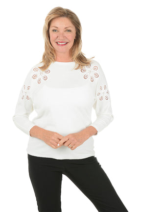 Woman wearing a white sweater with decorative cut-out patterns on a white background.