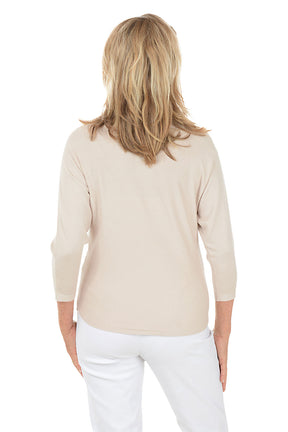 Woman wearing a beige sweater with floral embroidery on a white background. Back shot.