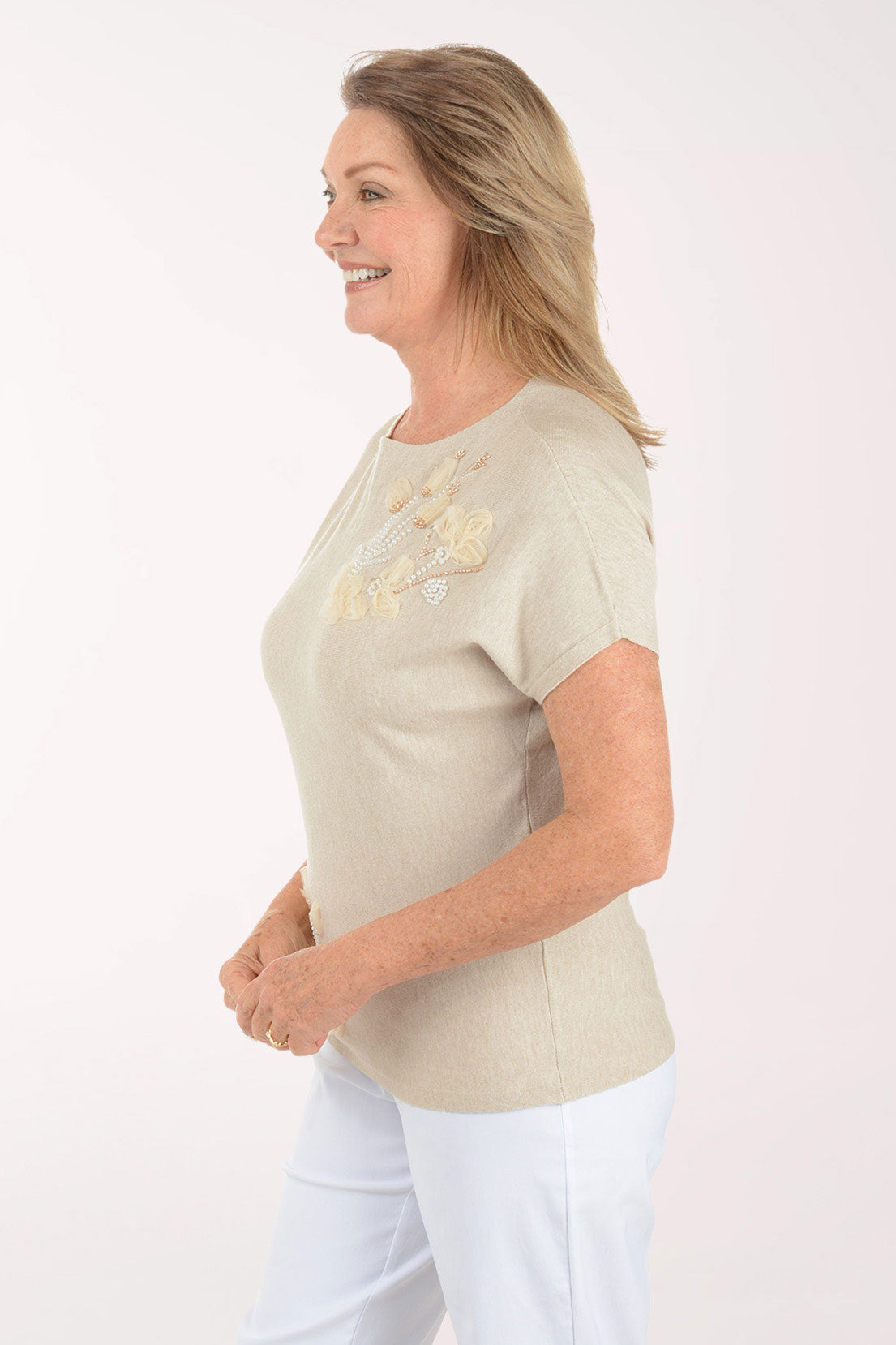 Woman wearing a beige t-shirt with floral embroidery on a white background