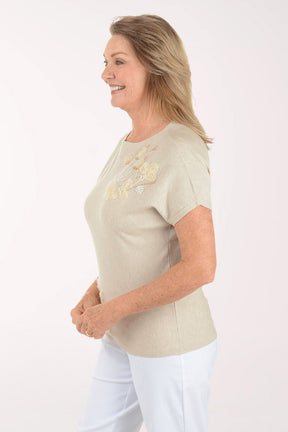 Woman wearing a beige t-shirt with floral embroidery on a white background