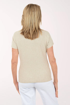 Woman wearing a beige t-shirt with floral embroidery on a white background