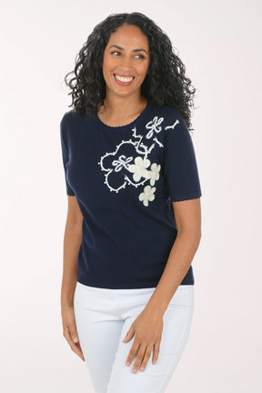 Woman wearing a navy blue t-shirt with floral designs on a white background