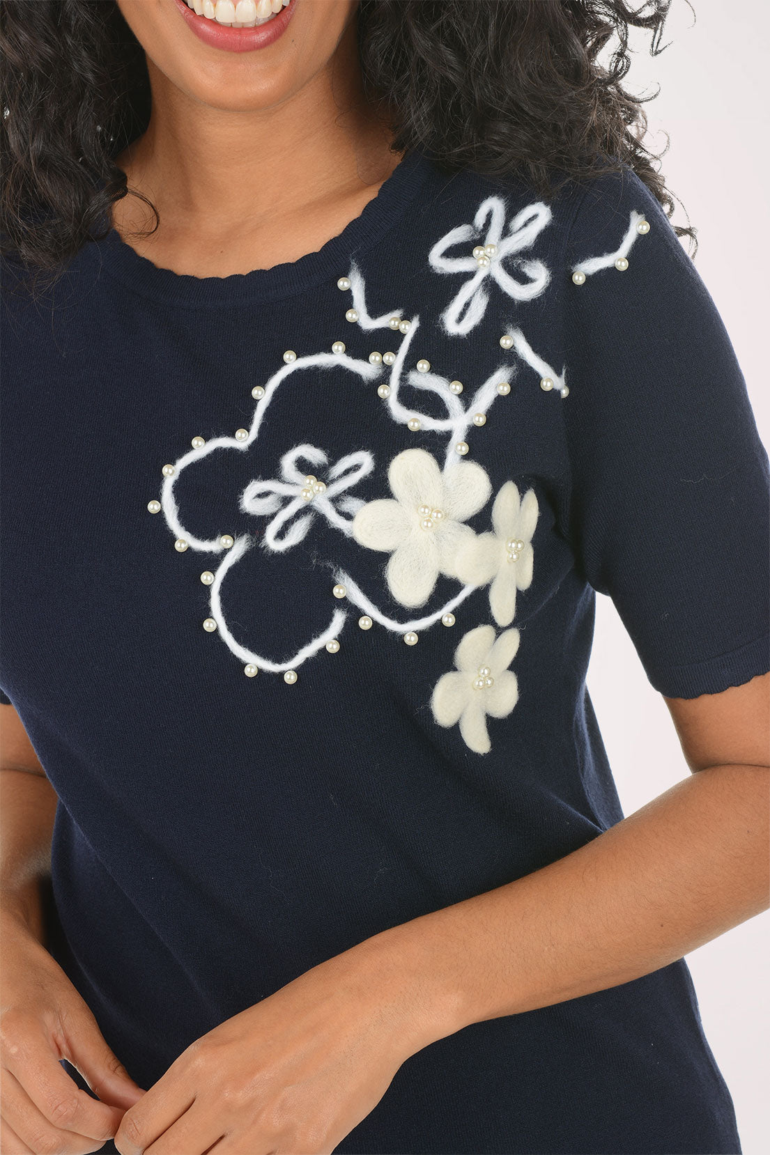 Woman wearing a navy blue t-shirt with floral designs on a white background