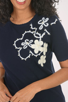 Woman wearing a navy blue t-shirt with floral designs on a white background