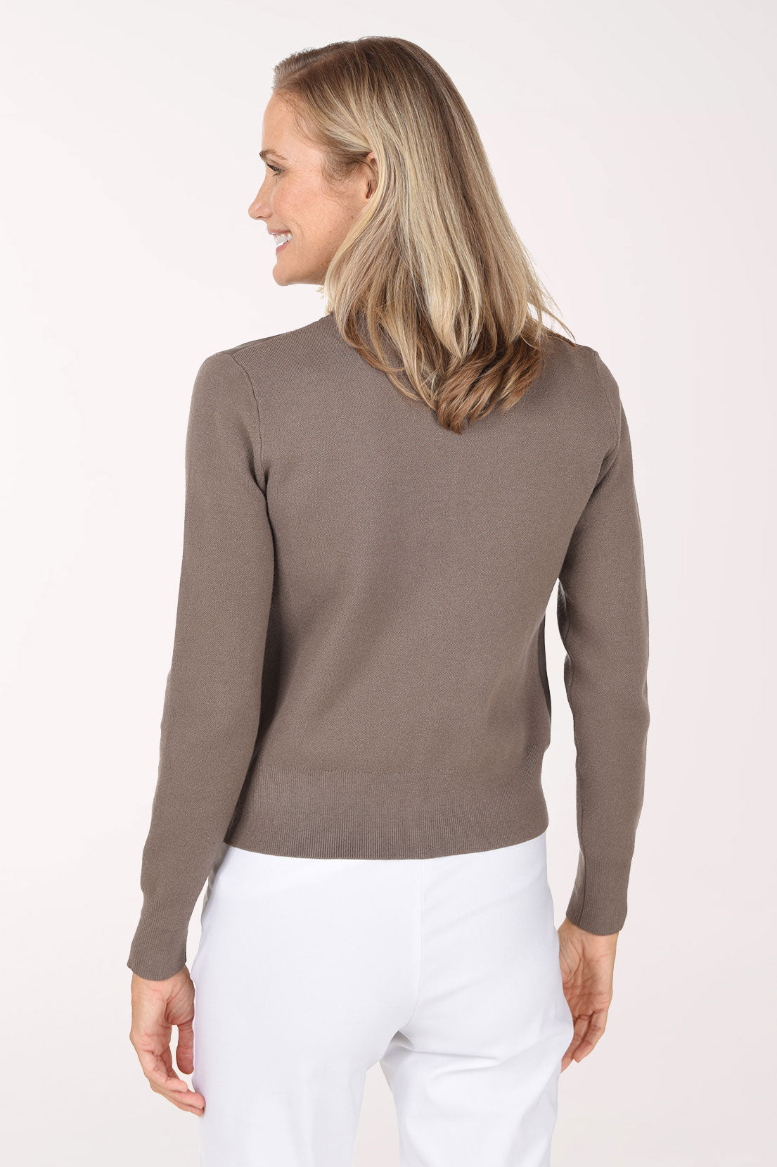 A smiling blonde woman wearing a taupe-brown zip-up jacket with a fuzzy suede-like texture over a white top, photographed against a clean white studio background.