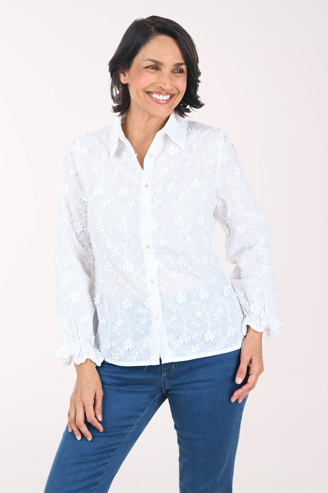 Woman wearing a white patterned shirt and blue pants on a white background