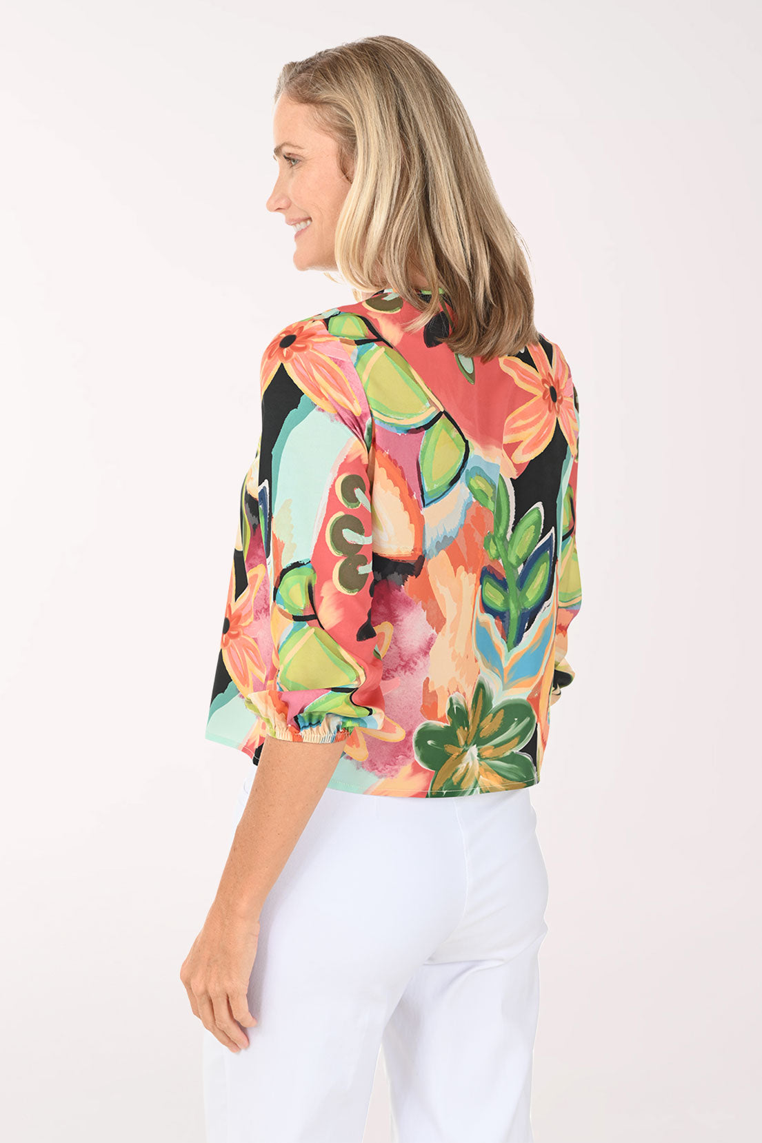 Woman wearing a v-neck multi colored top with a tie at the hemline.