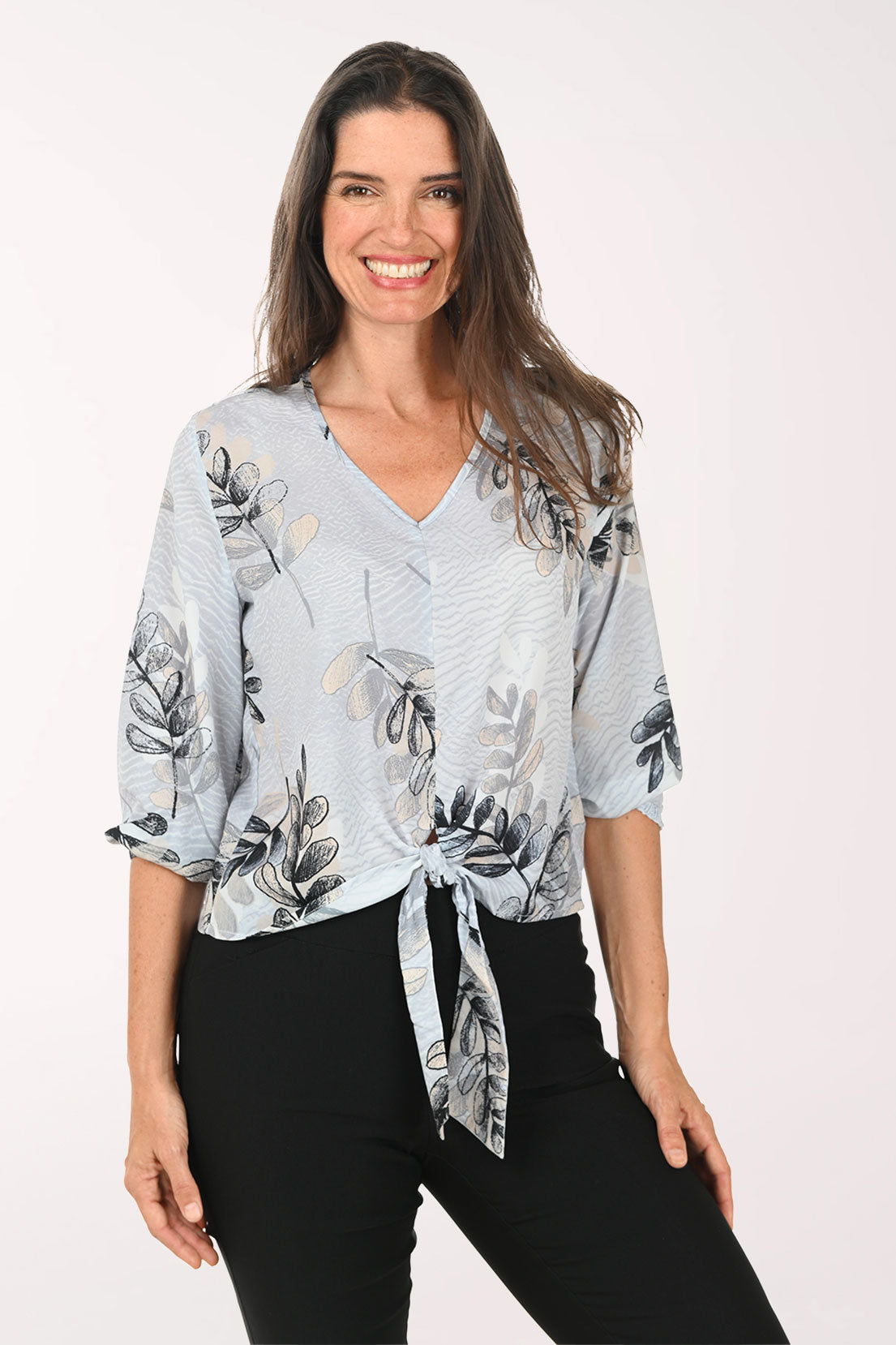 Woman wearing a grey v-neck top with a tie detail at the waist.