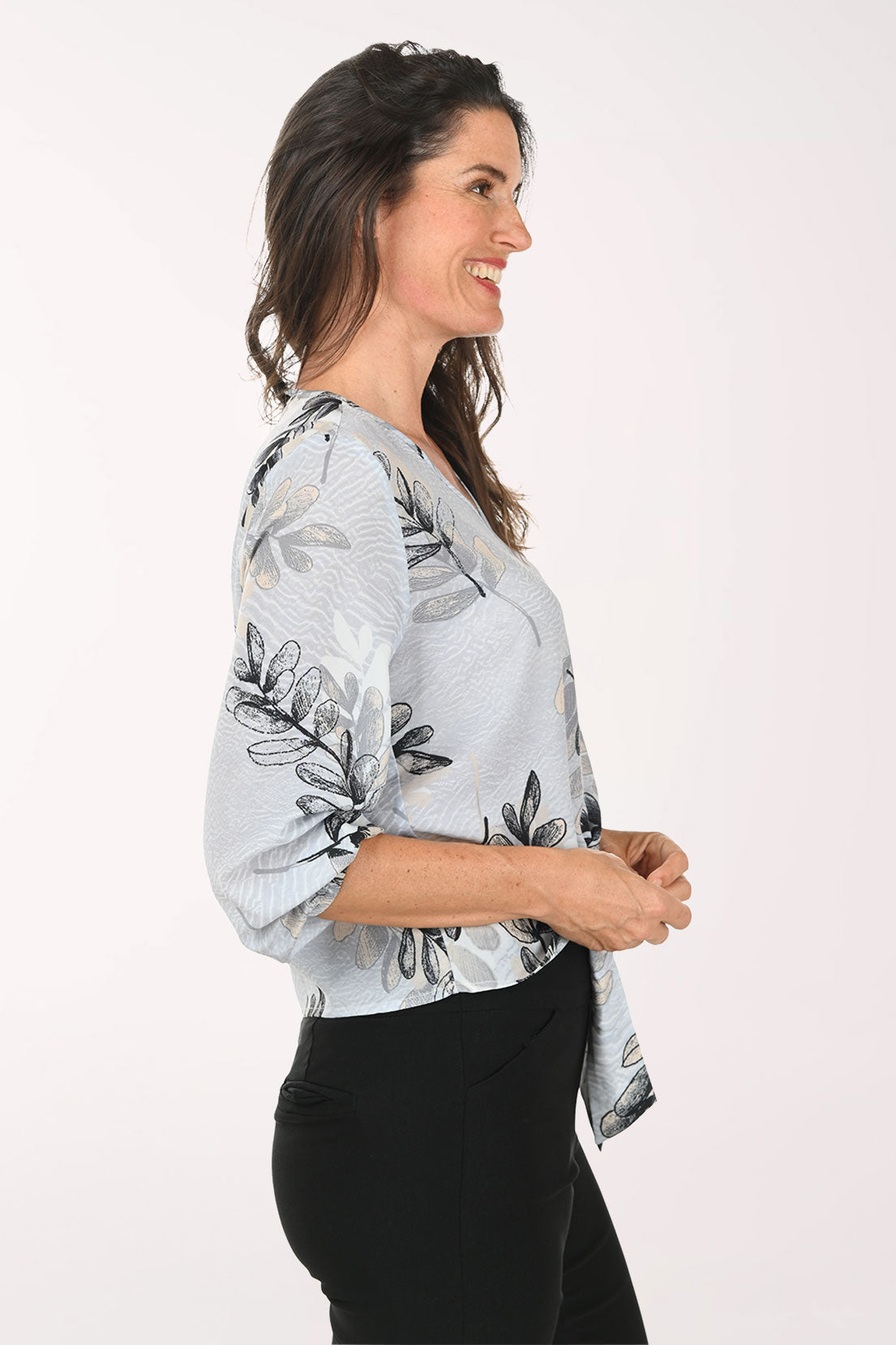 Woman wearing a grey v-neck top with a tie detail at the waist.