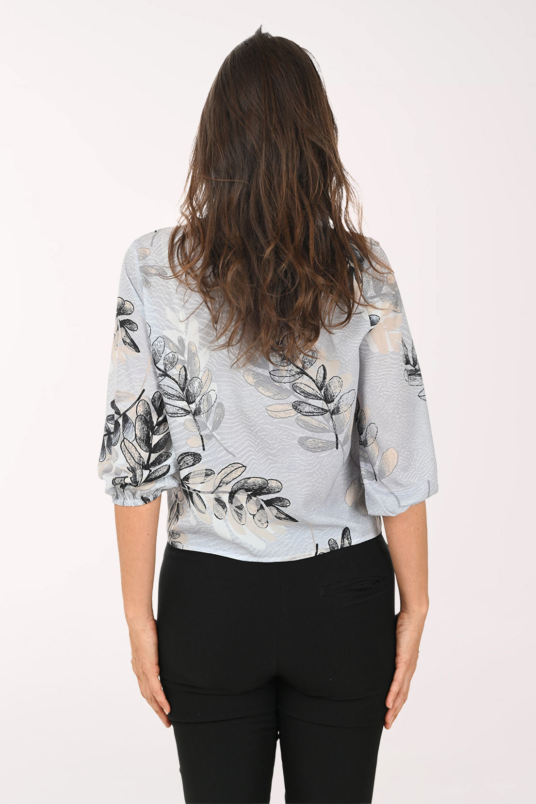 Woman wearing a grey v-neck top with a tie detail at the waist.