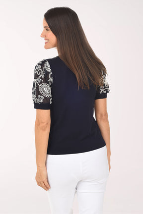 Woman wearing a black top with white patterned sleeves on a white background