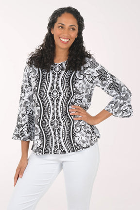 Woman wearing a black and white patterned blouse with white pants on a white background