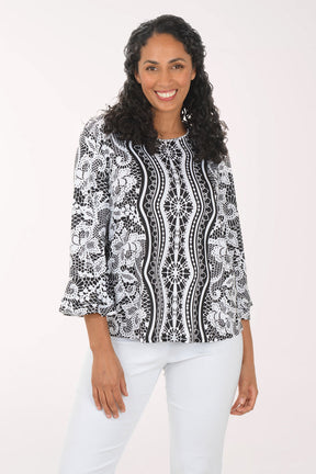 Woman wearing a black and white patterned blouse with white pants on a white background