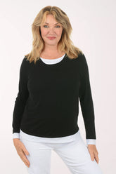 Woman wearing a black long-sleeve top and white pants on a white background