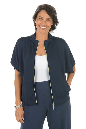 Woman wearing a navy blue zip-up top with a white background. Unzipped.