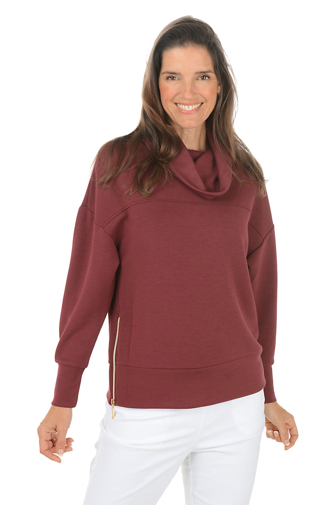 Woman wearing a maroon cowl-neck sweater and white pants on a white background