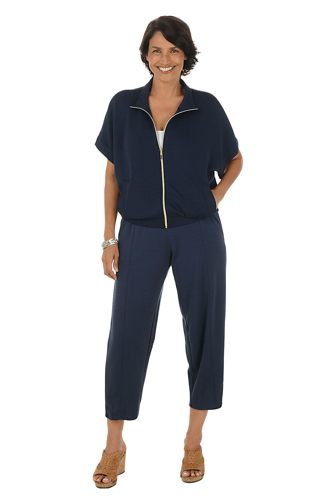 Woman wearing a navy blue outfit with blue barrel trousers on a white background.