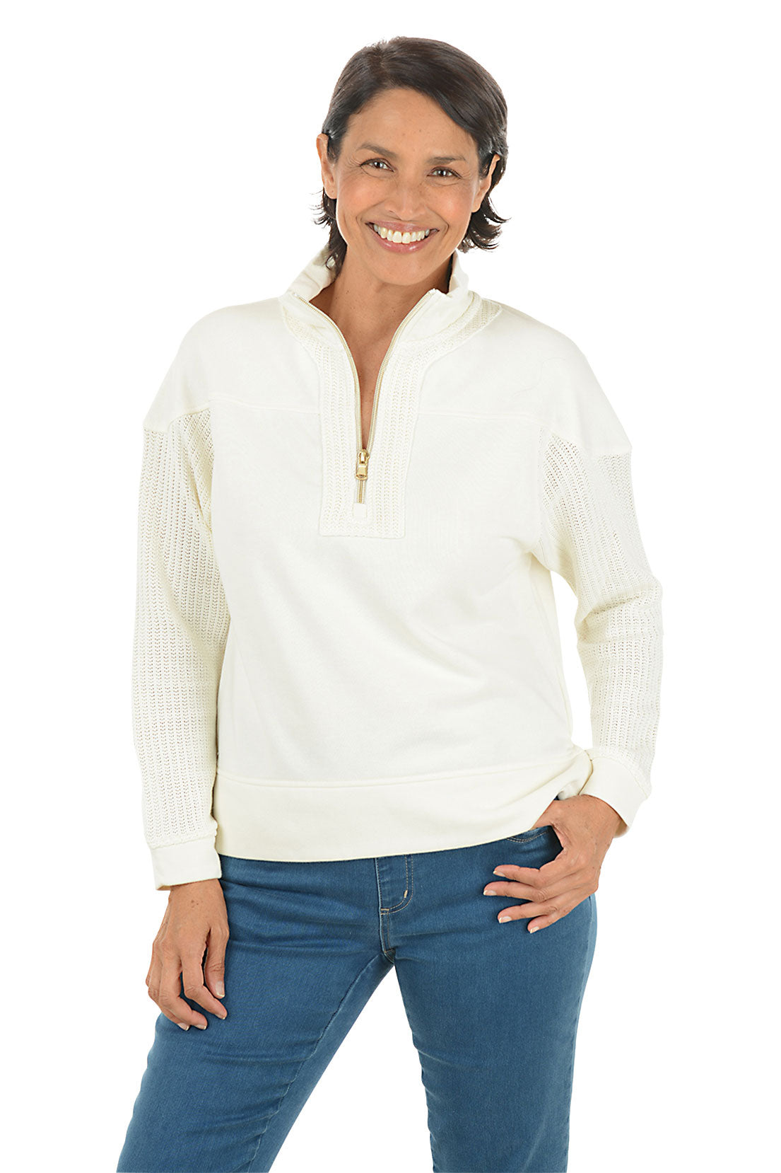 Woman wearing a white pullover with a quarter zip and denim pants on a white background