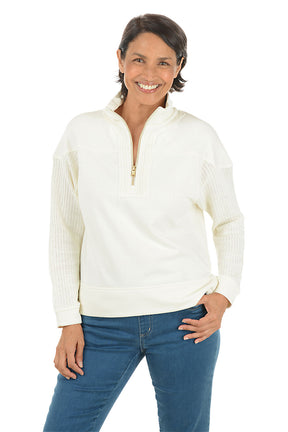 Woman wearing a white pullover with a quarter zip and denim pants on a white background