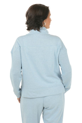 Woman wearing a light blue pullover with a quarter zip and matching pants on a white background. Back shot.