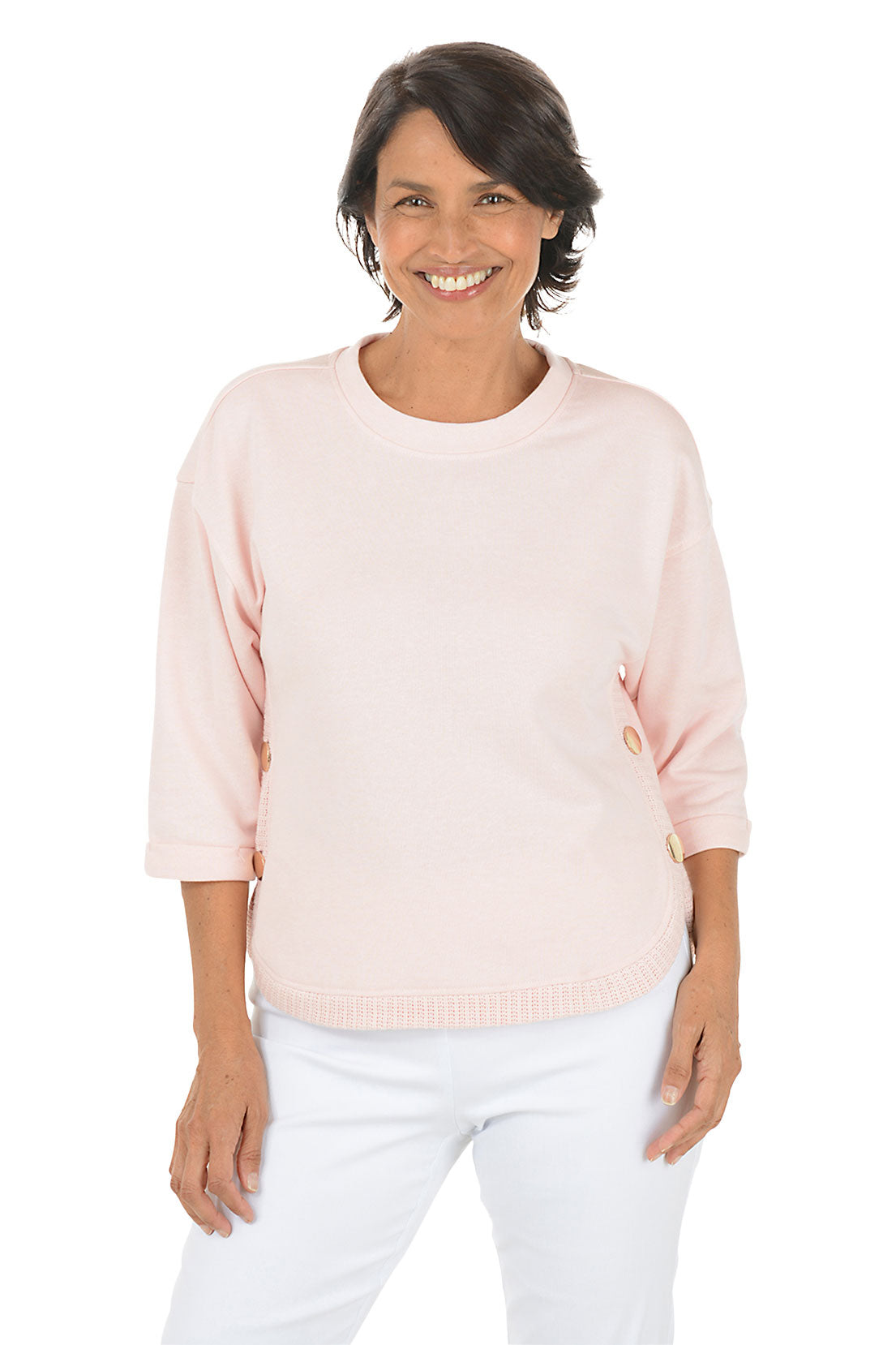 Woman wearing a light pink sweater and white pants on a white background
