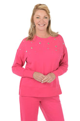 Woman wearing a pink sweatshirt with embellishments on a white background