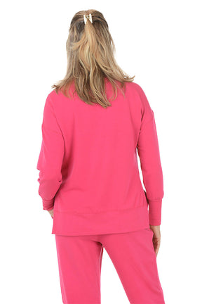 Woman wearing a pink sweatshirt with embellishments on a white background. Back shot.