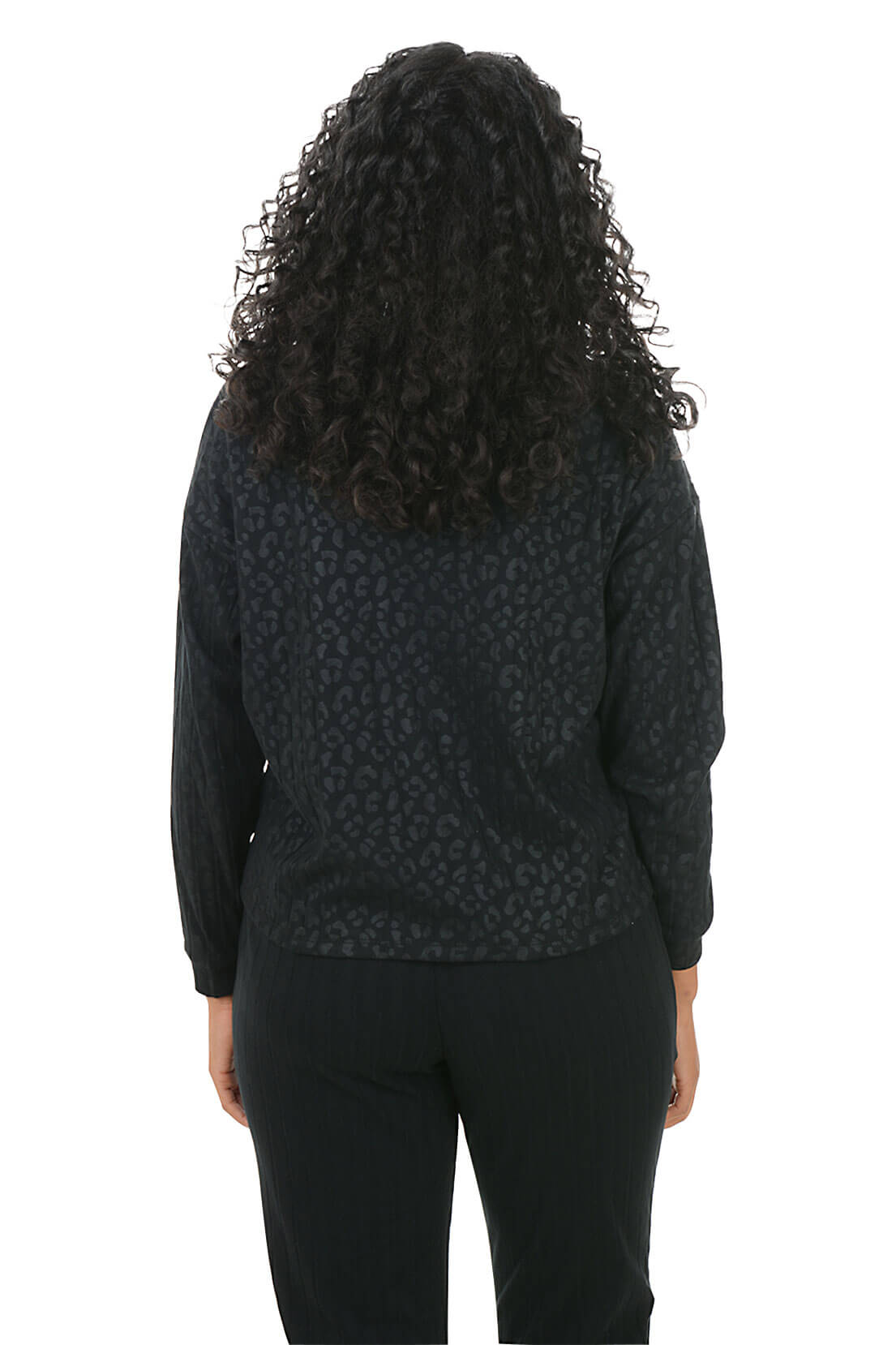 Person wearing a black patterned top and black pants on a white background