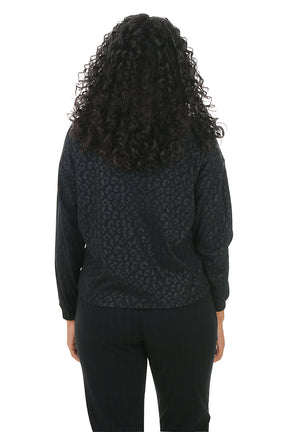 Person wearing a black patterned top and black pants on a white background