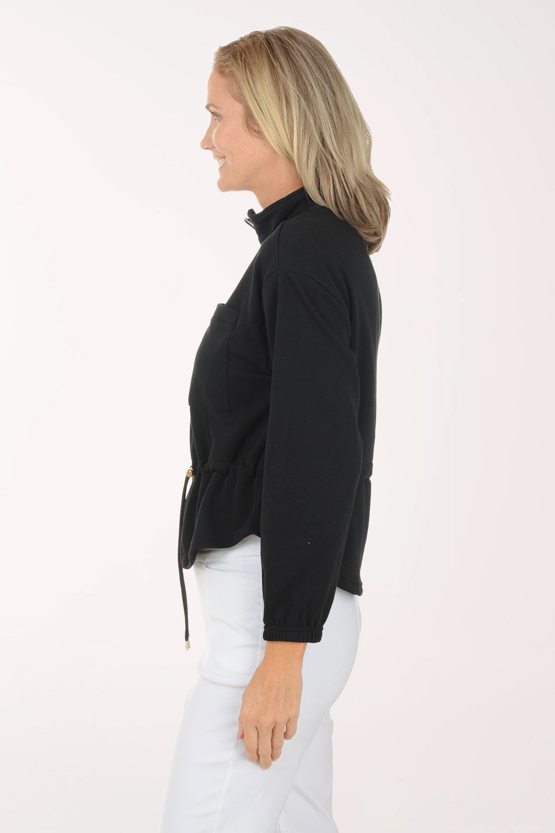 Woman wearing a black long-sleeve top and white pants on a white background
