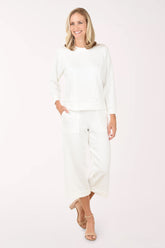 Woman wearing a white outfit on a plain background