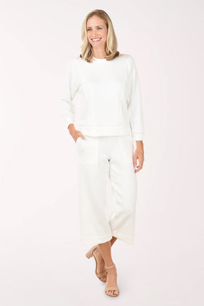 Woman wearing a white outfit on a plain background