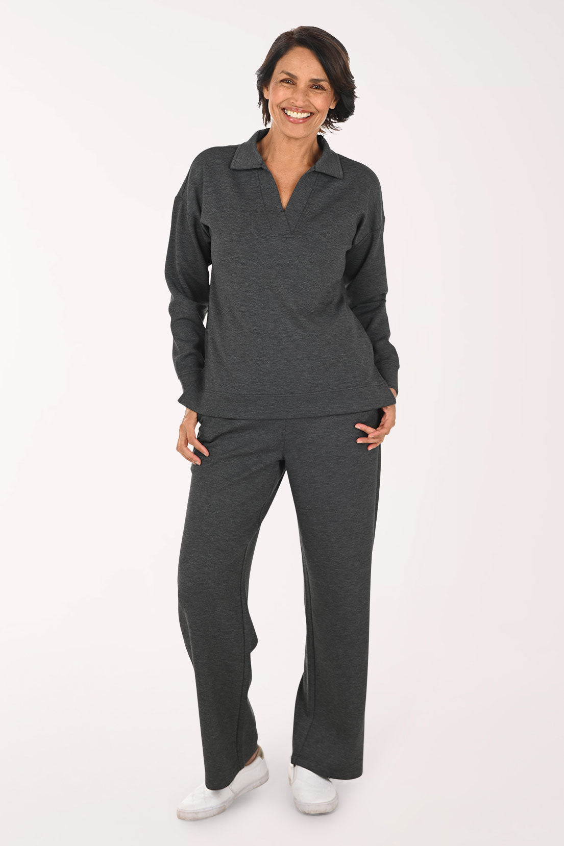 A person wearing dark heather gray wide-leg pants with side pockets, paired with a white top and white sneakers, shown against a plain light background.