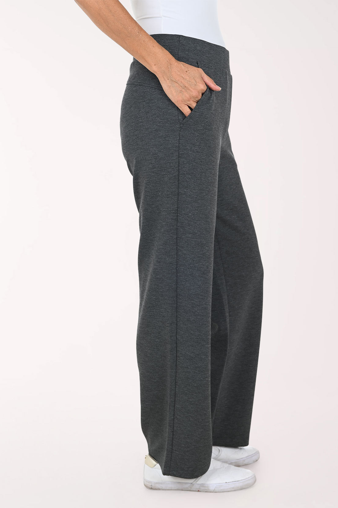 A person wearing dark heather gray wide-leg pants with side pockets, paired with a white top and white sneakers, shown against a plain light background.