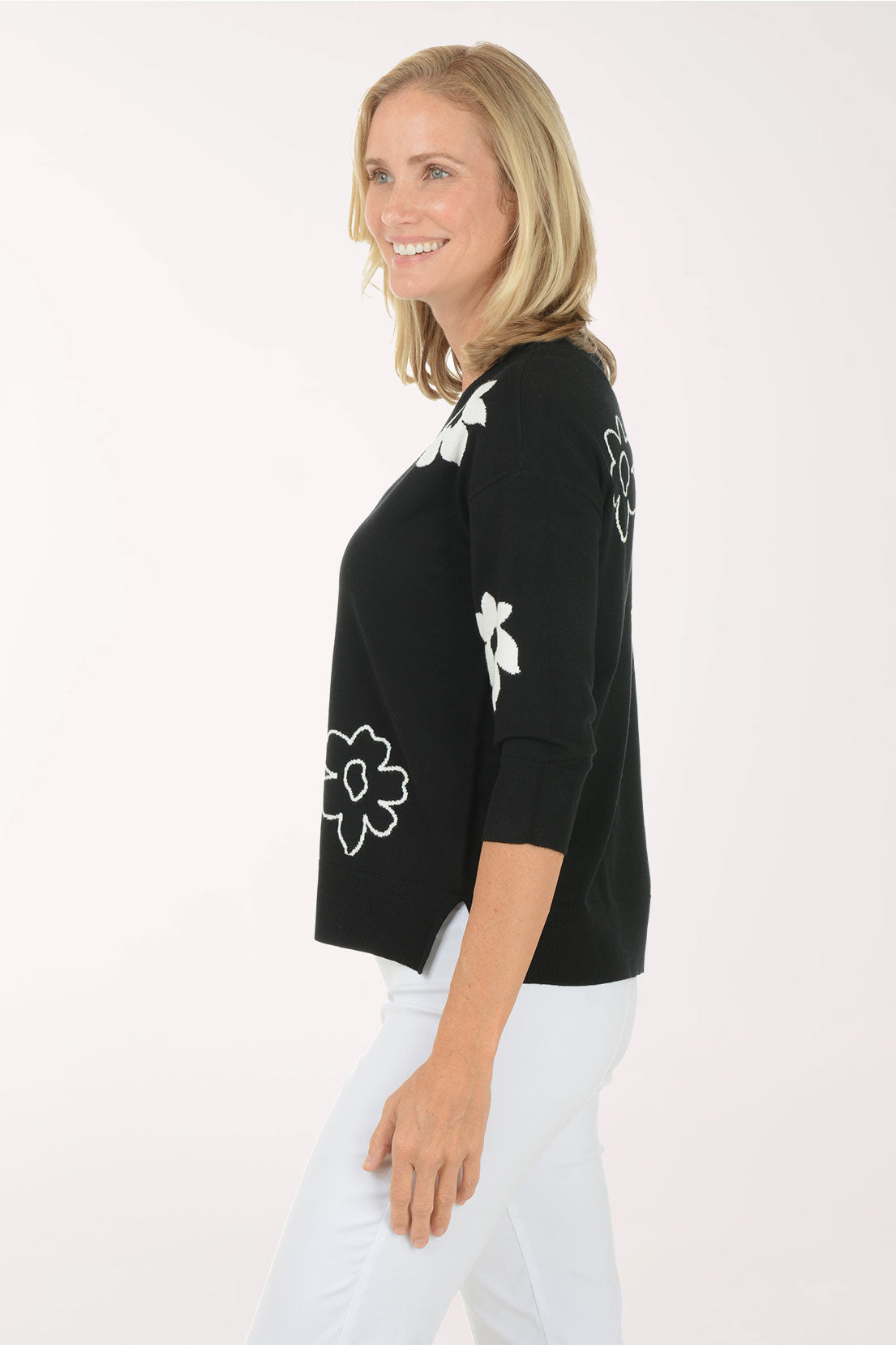 Woman wearing a black sweater with white floral patterns on a white background