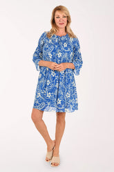 Woman wearing a blue flowy dress with 3/4 sleeves and a flower print