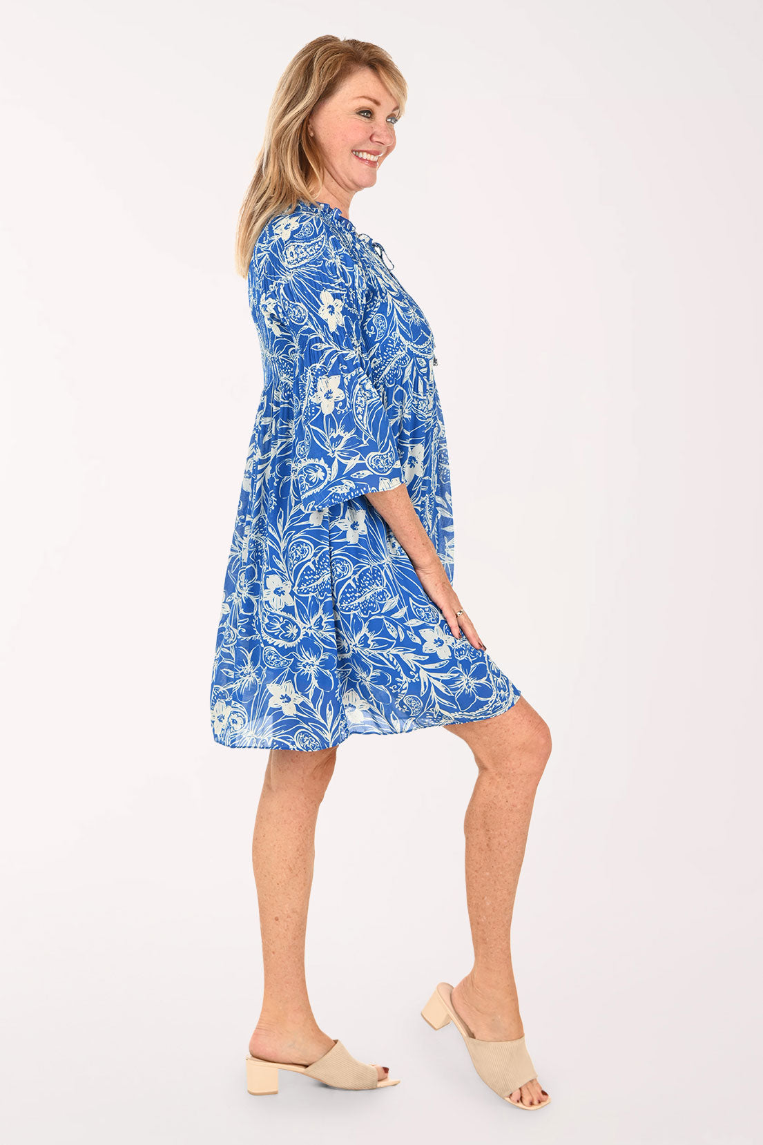 Woman wearing a blue flowy dress with 3/4 sleeves and a flower print
